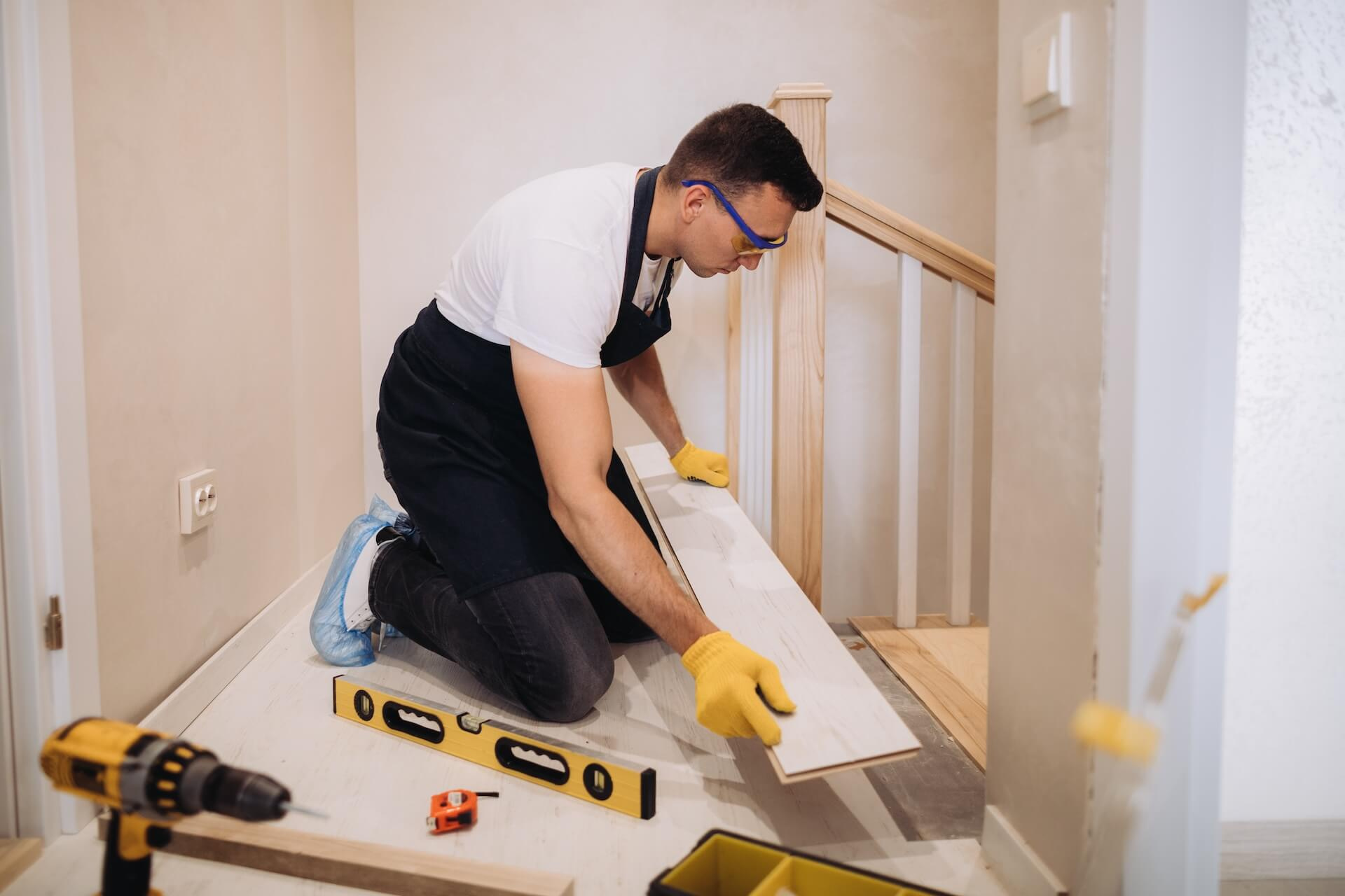 En hantverkare som lägger golv vid toppen av en trappa, ett vanligt moment i samband med en trapprenovering.