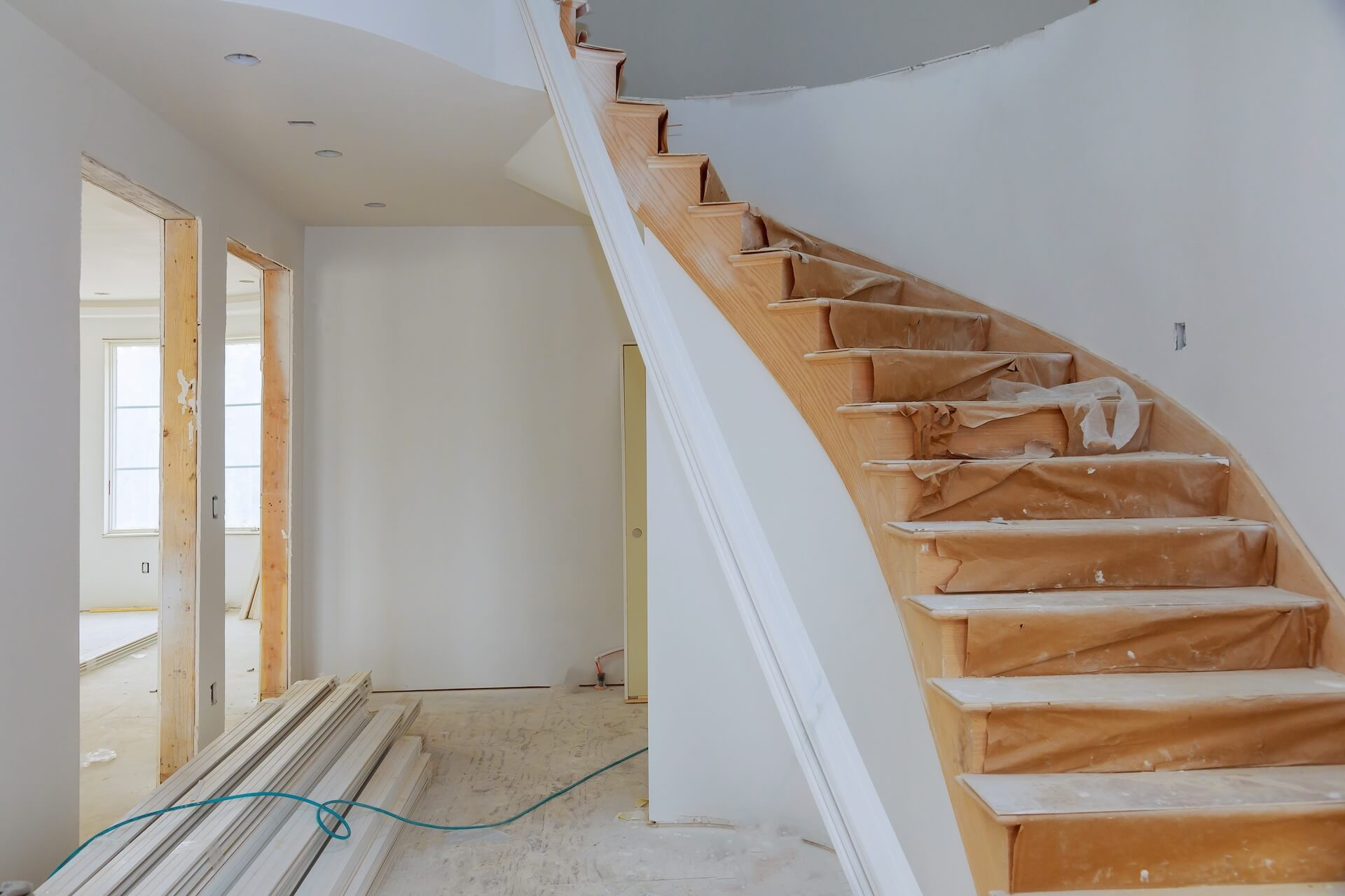 En svängd trätrappa täckt med skyddspapper under en pågående trapprenovering i ett hem.